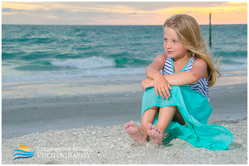 Young girl in dress sitting on beach